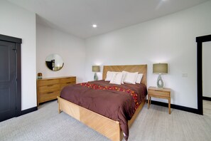 A bedroom with a wooden bed, two bedside tables with lamps, a dresser, and a mirror on the wall.