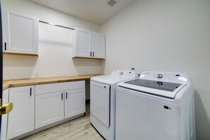 A laundry room with white cabinets, a wooden countertop, and two white washing machines. - Brand-New Luxury Estate with Expansive Mtn Views! (Donnelly)