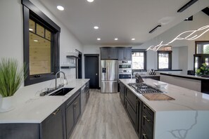 A modern kitchen with a central island, stainless steel appliances, and a large window providing natural light.