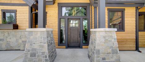 A wooden building with a stone entrance, large windows, and a covered porch area.
