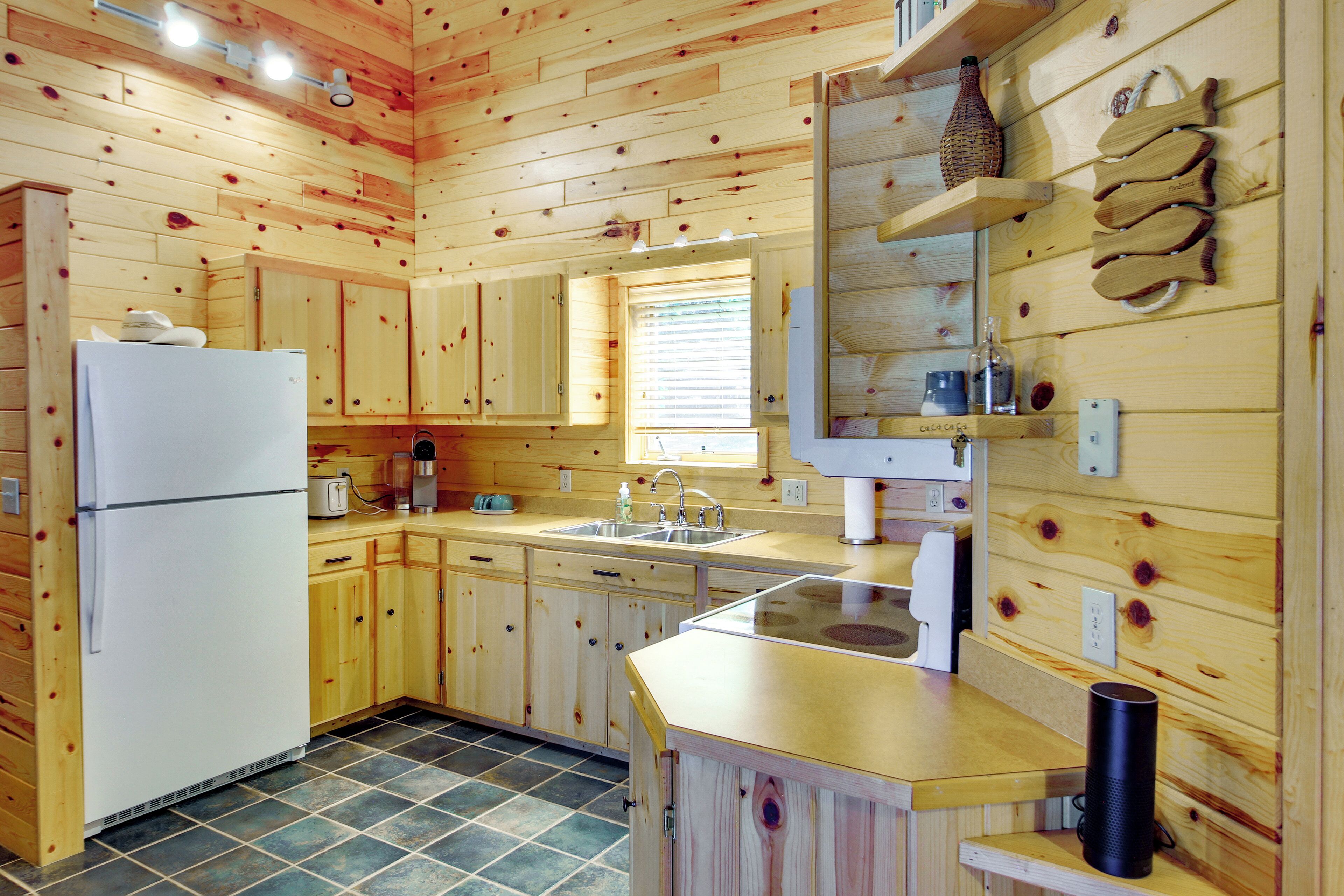 A wooden cabin kitchen with a refrigerator, sink, and wooden cabinets.