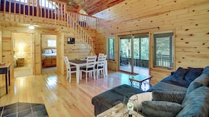 A wooden cabin interior with a dining area, a sofa, a staircase, and a balcony. - Fire Pit & Screened Porch! 3.5-Acre Nevis Retreat (Nevis)