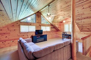 Ein gemütliches Dachzimmer mit eingebautem Sofa, Fernseher und Esstisch.
