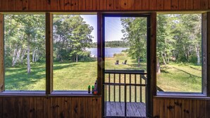 A wooden cabin with a large window overlooking a grassy area and a lake. - Fire Pit & Screened Porch! 3.5-Acre Nevis Retreat (Nevis)