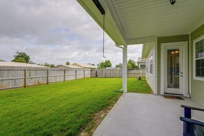 A residential backyard with a covered patio, a lawn, and a wooden fence. - Near Tyndall AFB & the Beach! Panama City Retreat (Panama City)