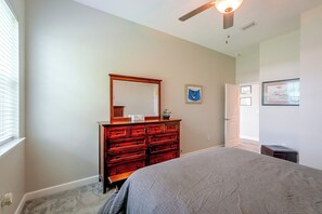 Un dormitorio con cama, cómoda y ventilador de techo.