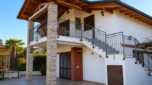 Una casa de dos pisos con un balcón, una escalera y una puerta.