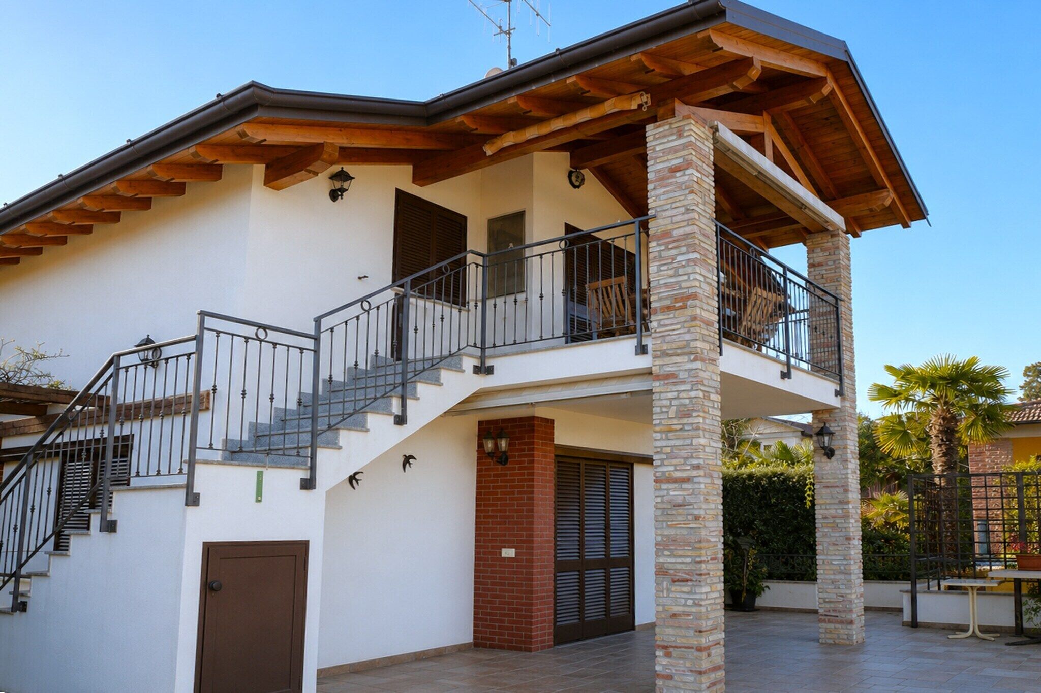 A two-story house with a balcony, a staircase, and a brick column.
