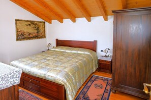 Ein Schlafzimmer mit einem hölzernen Bett, einem Nachttisch, einem Kleiderschrank, einem Bild an der Wand und einem gemusterten Teppich.
