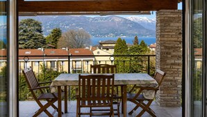Un balcón con mesa y sillas, con vistas a un paisaje montañoso y un lago.