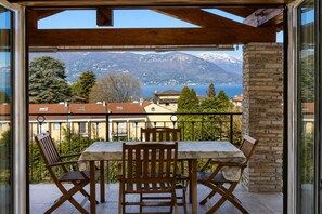 Ein Balkon mit Tisch und Stühlen, der einen Blick auf eine Berglandschaft und einen See bietet.