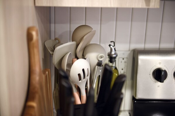 A kitchen utensil holder with various kitchen tools, a bottle of olive oil, and a stainless steel appliance. - HULU+GYM+PARKING Near Shopping|UPMC|Universities (Pittsburgh)