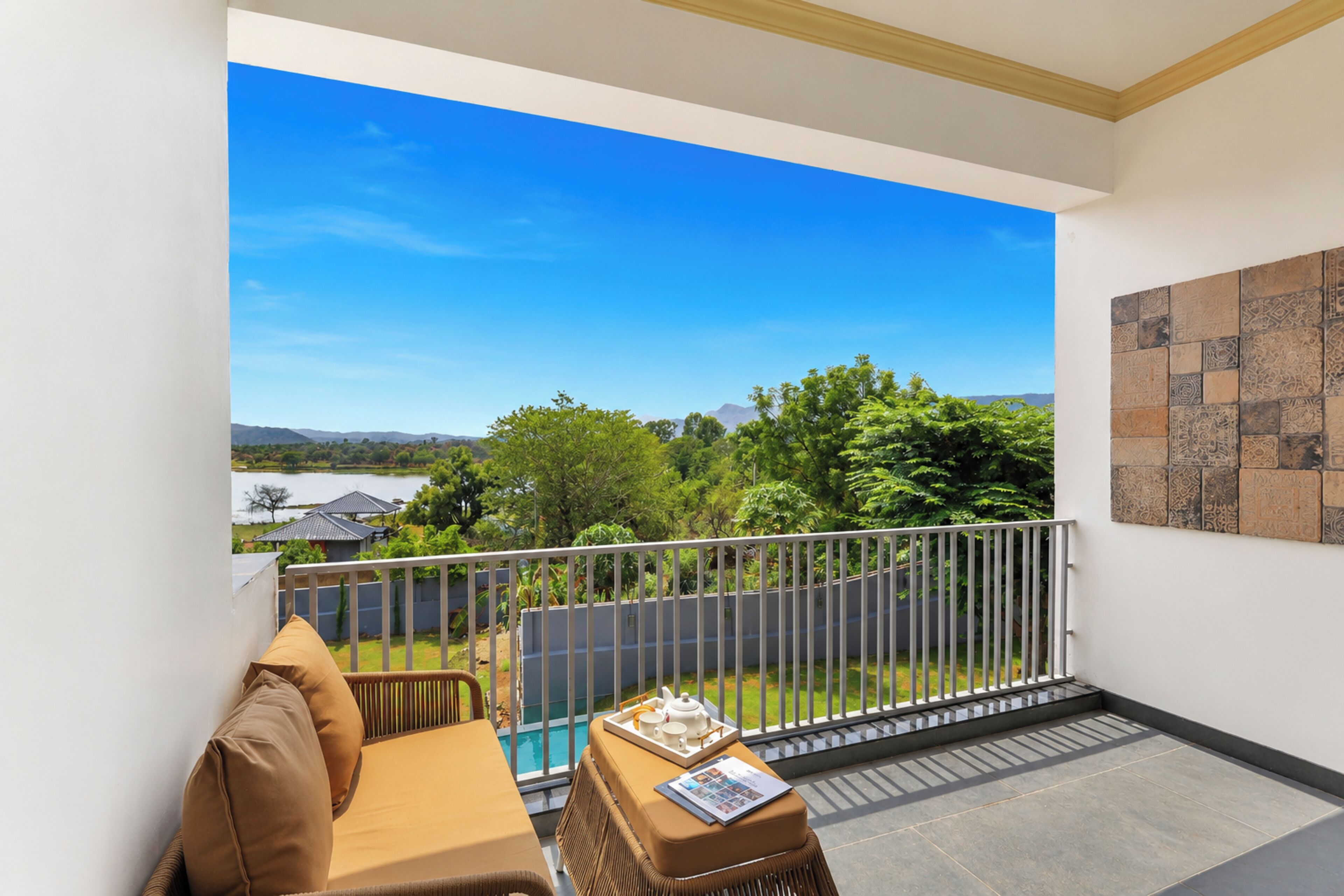A balcony with a view of a swimming pool, a sofa, and a table with a tray of items.