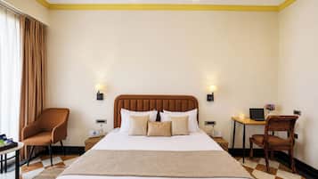 Habitación de hotel con una cama grande, dos mesitas de noche, un escritorio con silla, y una ventana con cortinas.
