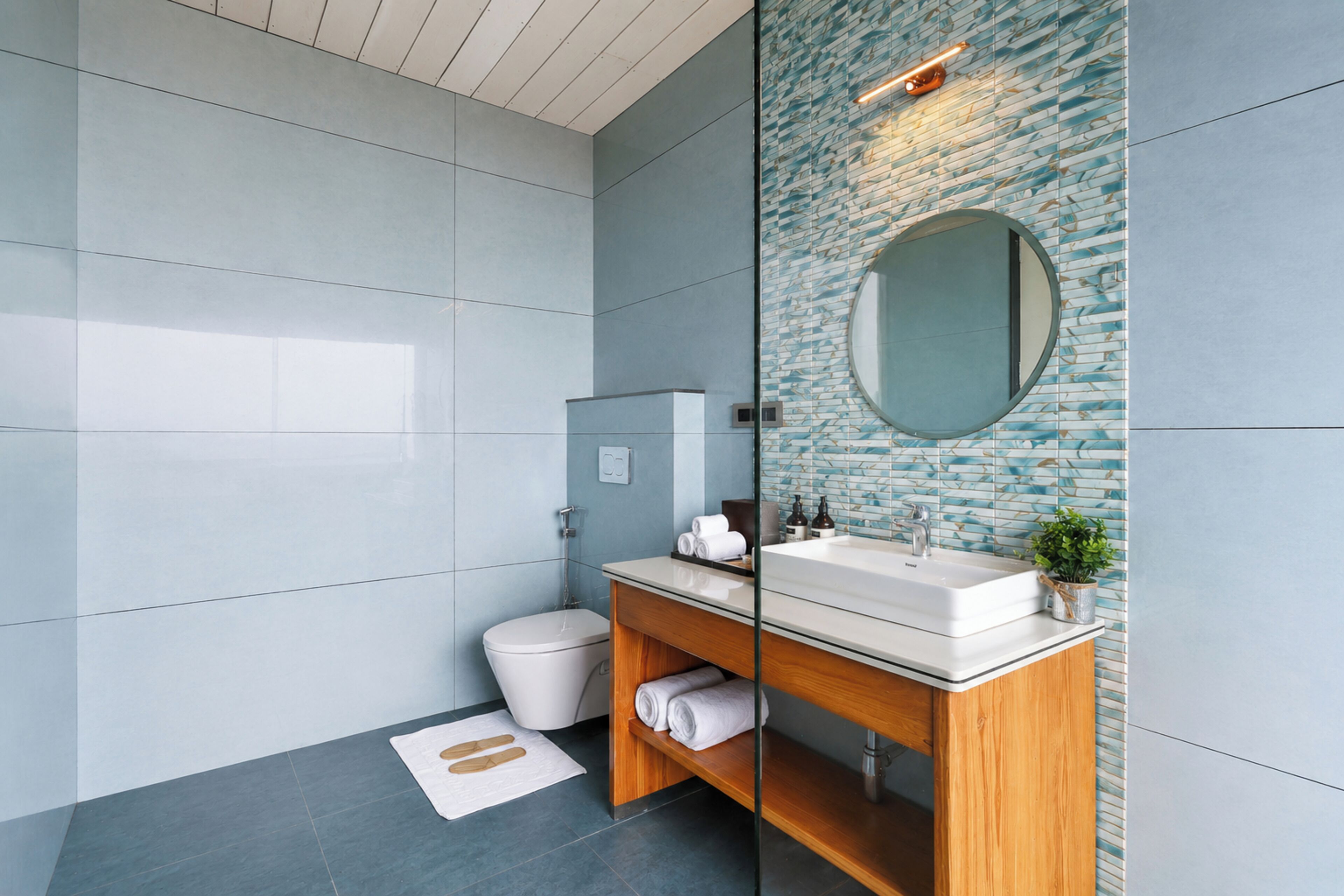 Une salle de bain moderne avec un grand miroir, des toilettes, un lavabo et une douche.