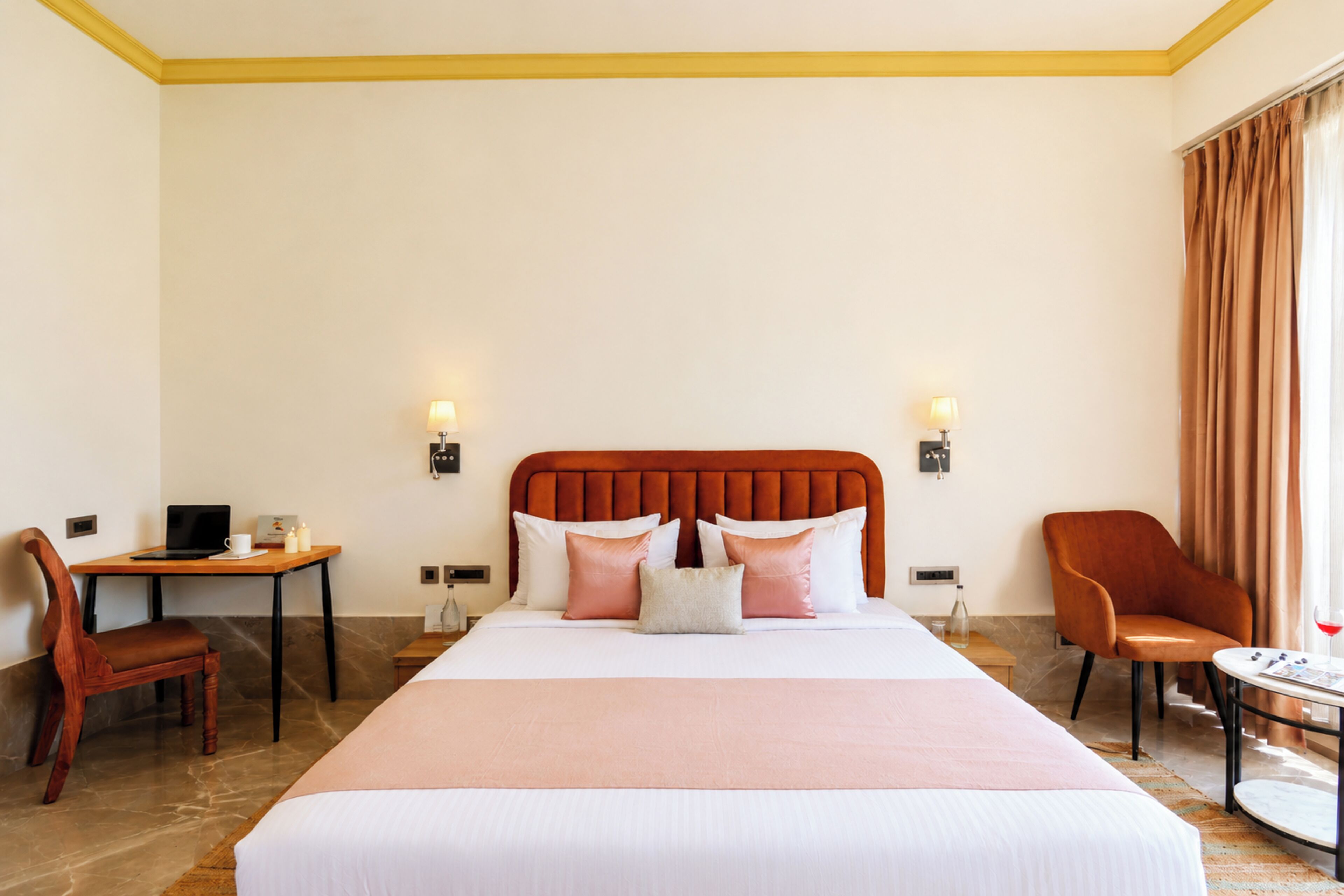 A hotel room with a large bed, a desk, a chair, and a small table.