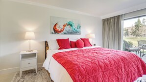 Et hotelværelse med en stor seng, et billede over sengen og udsigt til det fri gennem vinduet.