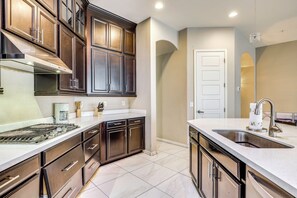 A kitchen with dark wooden cabinets, a stainless steel range hood, a white countertop, and a stainless steel sink. - 'Rapt Expression' Queen Creek Home w/ Patio! (Queen Creek)