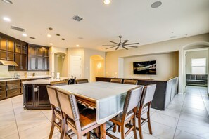 Una cocina moderna con armarios de madera oscura, una isla central y una zona de comedor con una mesa grande y sillas.