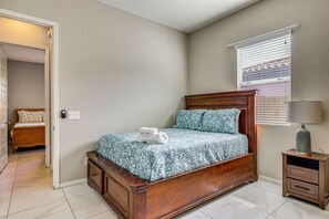 A bedroom with a wooden bed, a nightstand with a lamp, and a window with blinds. - 'Rapt Expression' Queen Creek Home w/ Patio! (Queen Creek)