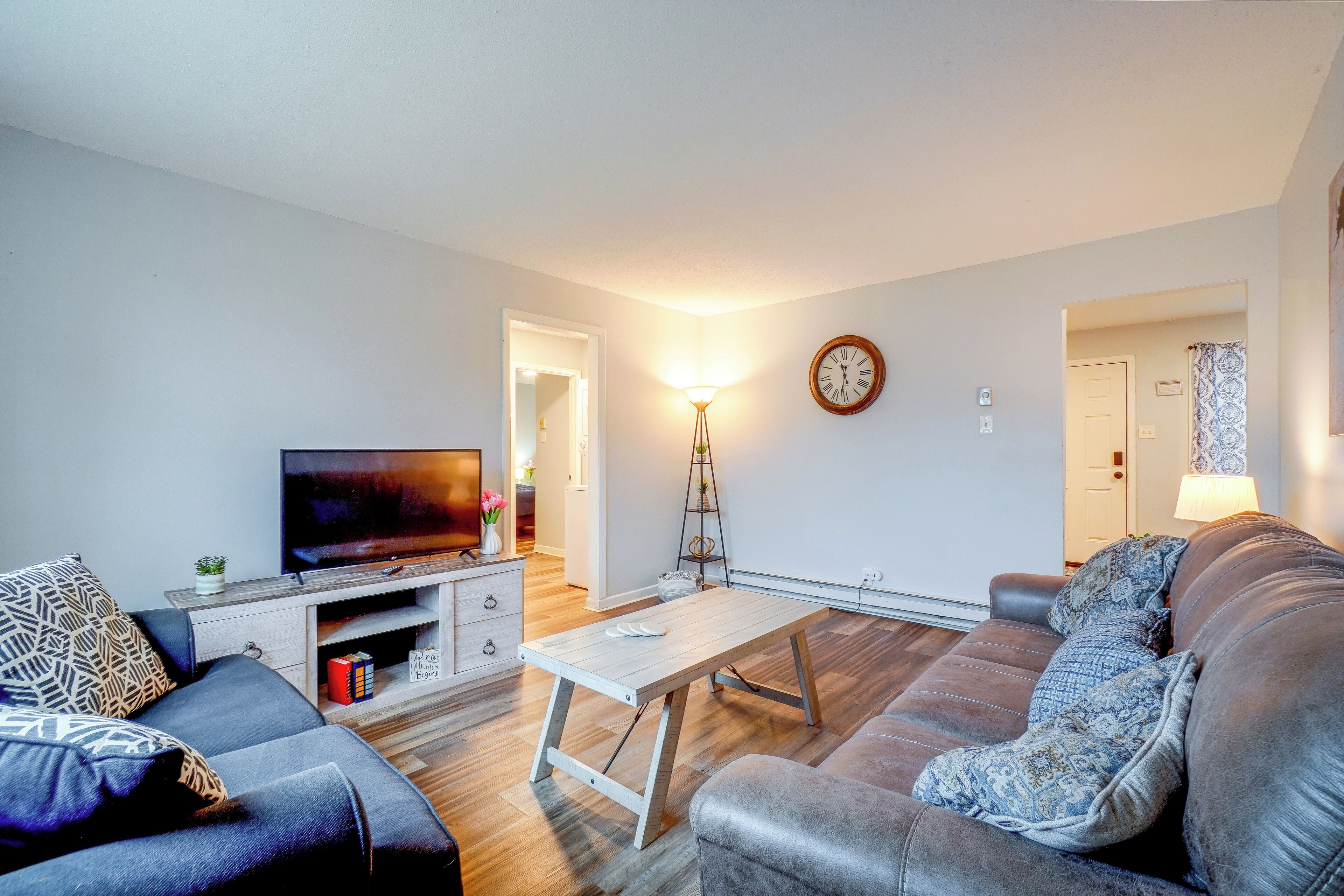 Ein Wohnzimmer mit Fernseher, Sofa, Couchtisch und einer Wanduhr.