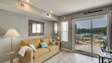 A living room with a sofa, a lamp, and a view of a lake through large glass doors.