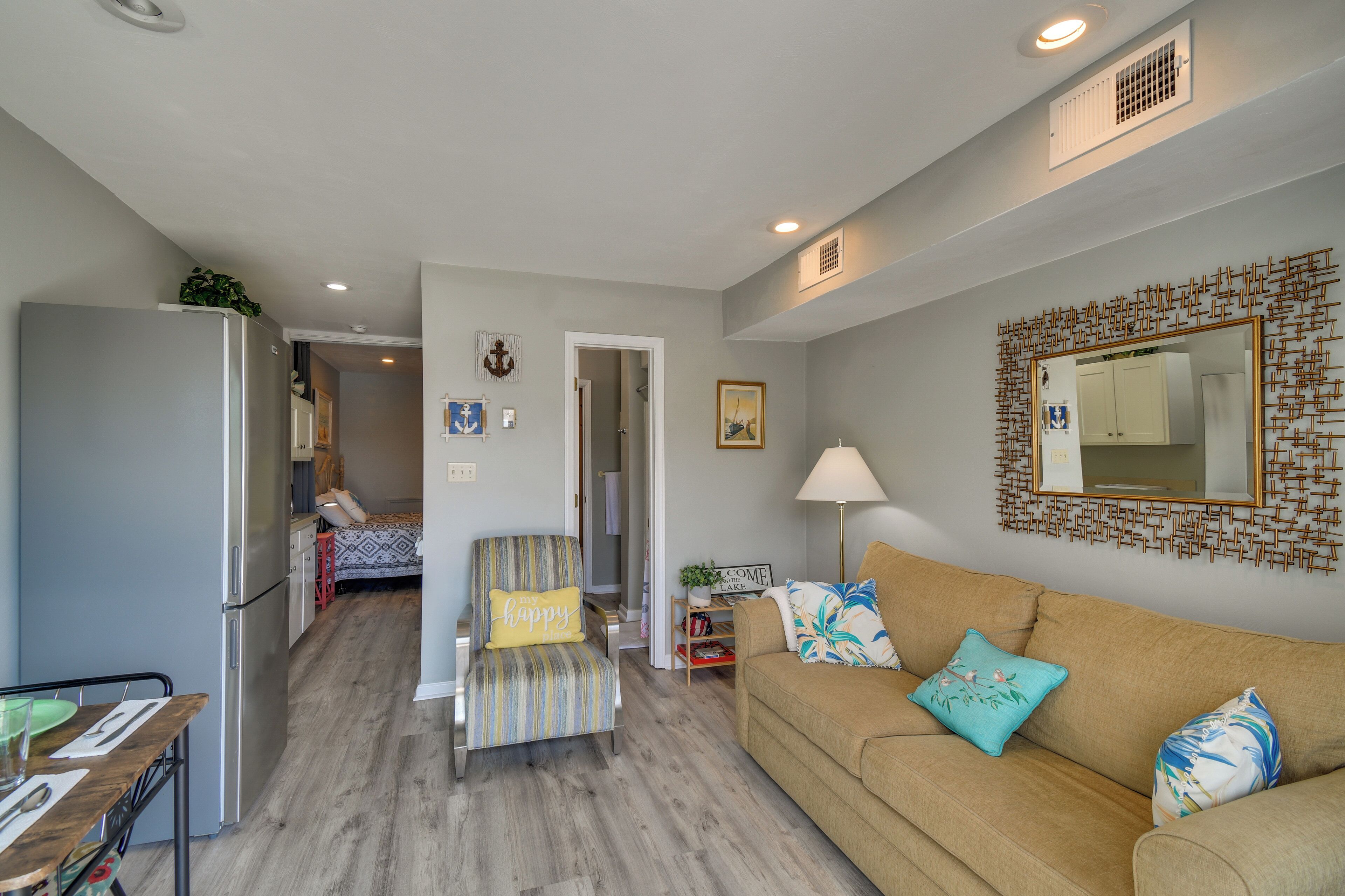 A compact living space with a kitchenette, a sofa, a chair, and a dining table.