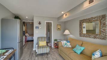 A compact living space with a kitchenette, a sofa, a chair, and a dining table.