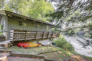 Una cabana amb un pont de fusta i una canoa.