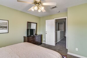 A bedroom with a bed, dresser, mirror, and a ceiling fan.