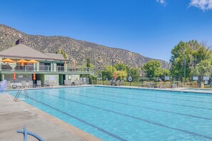 A swimming pool with lounge chairs and umbrellas, a covered area with a roof, and a mountainous backdrop. - Hike, Swim & Relax: Pine Mountain Club Escape! (Frazier Park)