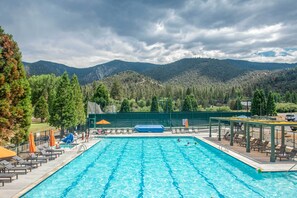 A swimming pool with lounge chairs and umbrellas, surrounded by a fence and trees, with mountains in the background. - Hike, Swim & Relax: Pine Mountain Club Escape! (Frazier Park)