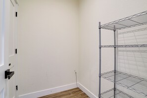 Een hoek van een kamer met een witte muur, een houten vloer en een metalen schapkast tegen de wand.