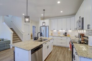 A modern kitchen with white cabinetry, a stainless steel refrigerator, a dishwasher, and a granite countertop. - Updated Family Home w/ Patio in Brighton (Brighton)