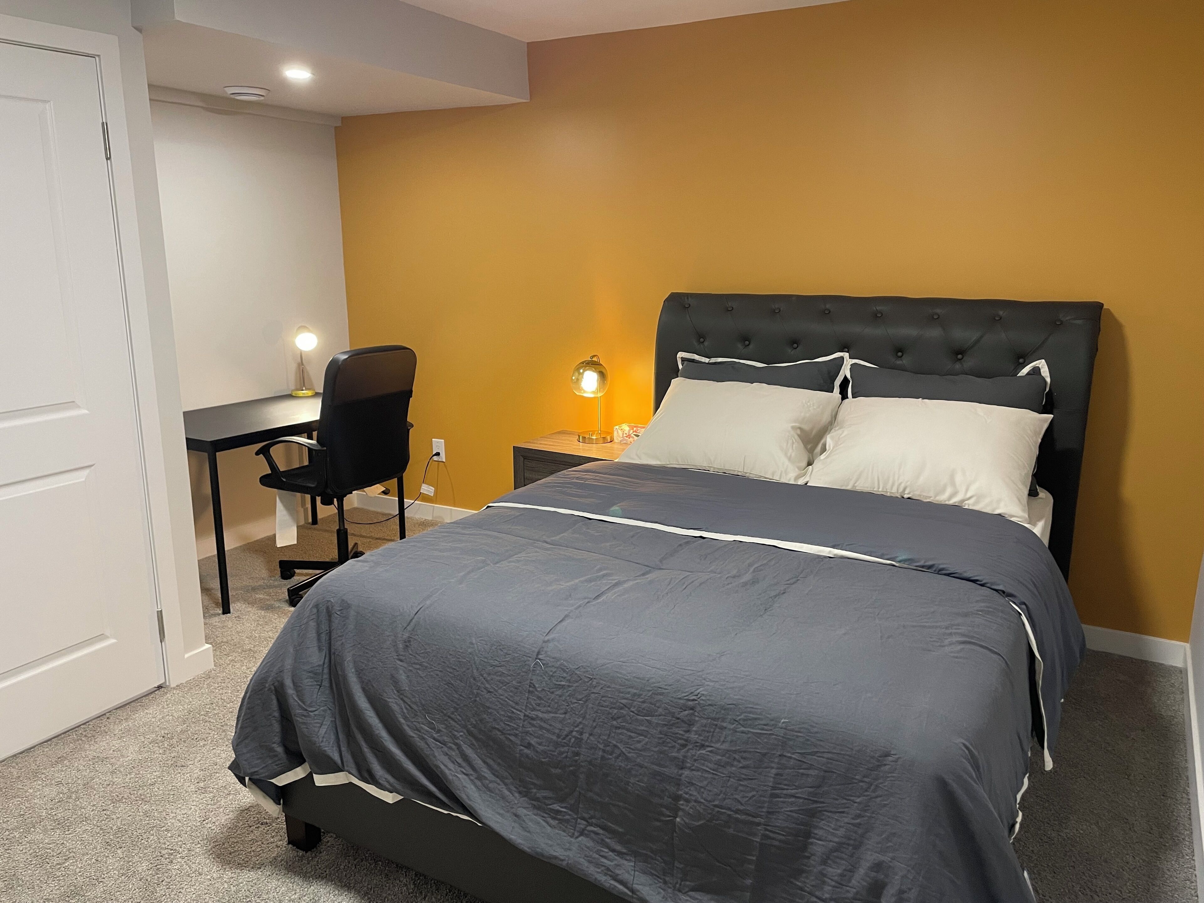 Un dormitorio con cama, escritorio y una silla.