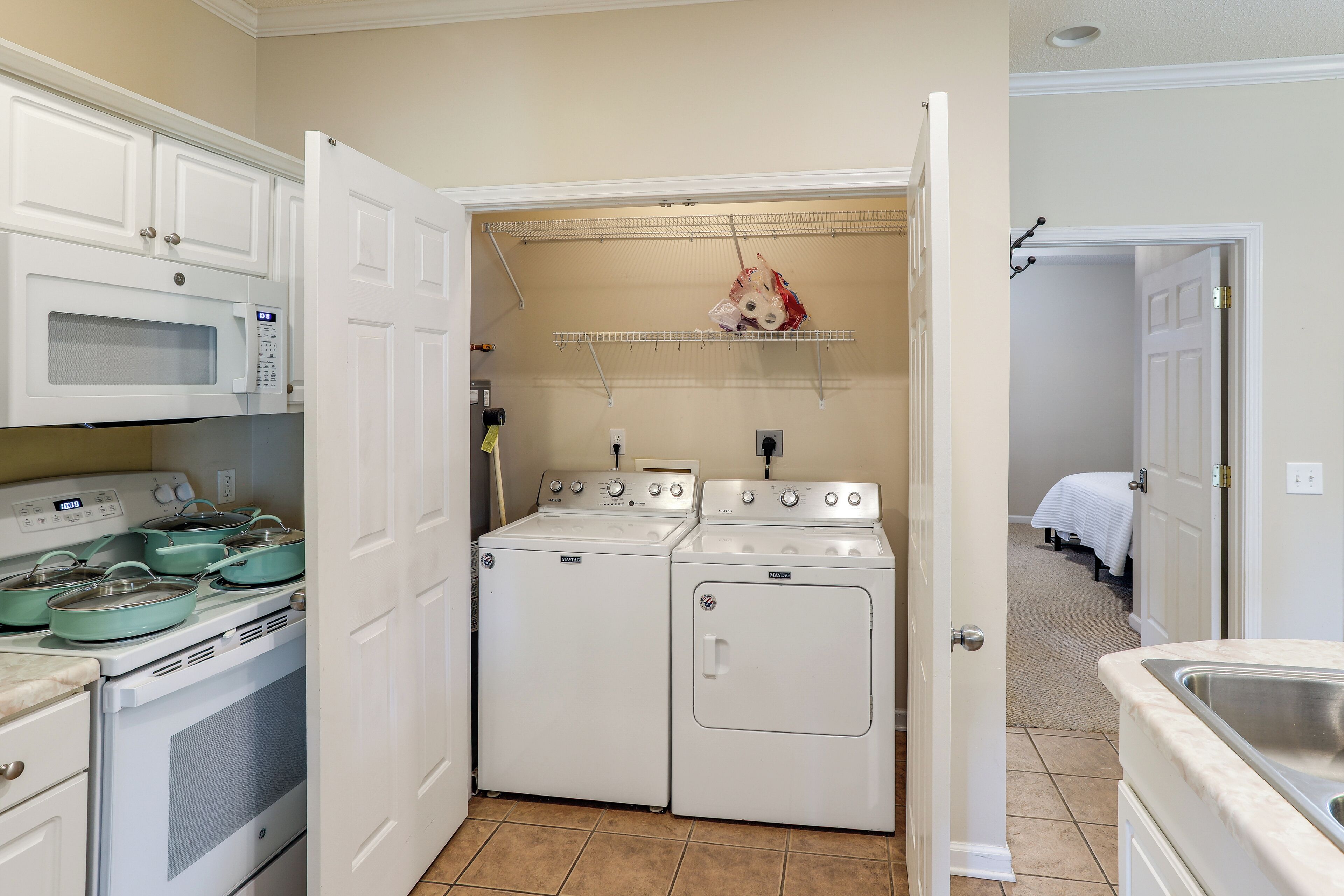 A compact kitchen with a microwave, stove, and oven. There is a laundry area with a dryer and washing machine.