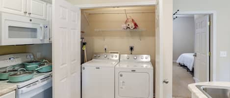 A compact kitchen with a microwave, stove, and oven. There is a laundry area with a dryer and washing machine.