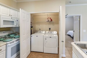 A compact kitchen with a microwave, stove, and oven. There is a laundry area with a dryer and washing machine.