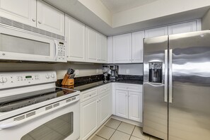 A modern kitchen with white cabinetry, a stainless steel refrigerator, a microwave, and a stove. - Tee Times & Pool Vibes! North Myrtle Beach Retreat (North Myrtle Beach)