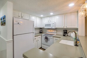 A kitchen with white cabinets, a refrigerator, a microwave, an oven, a coffee maker, and a sink. - Walk to Beach! Set of 2 St Augustine Condos (Saint Augustine Beach)