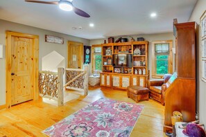 A cozy living room with a wooden floor, a large bookshelf, a television, and a comfortable seating area. - Walk to Blue Ridge Parkway! Family Home w/ Hot Tub (Blowing Rock)