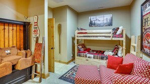 Um quarto acolhedor com uma cama beliche, uma cadeira de madeira, uma mesa pequena e uma prateleira fixada na parede.