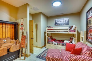 Ein gemütliches Zimmer mit einem Etagenbett, einem hölzernen Stuhl, einem kleinen Tisch und einem an der Wand befestigten Regal.