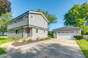 A two-story residential house with a garage, a front porch, and a well-maintained lawn. - Walk to Beach! McCullom Lake Family Getaway (McHenry)