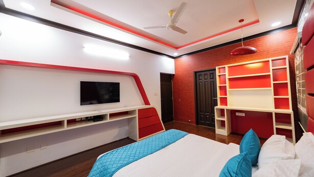 A modern bedroom with a bed, TV, and built-in shelving. - ELIVAAS Gerrys 4BHK Villa with Terrace (Chennai)