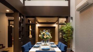 Uma sala de jantar moderna com teto alto, um candelabro e uma mesa posta para quatro pessoas.