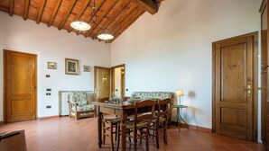 A dining area with a wooden table, chairs, and a sofa. There are two wooden doors, a radiator, and a lamp. - Vacation Home in Lamporecchio with 1 bedrooms sleeps 4 (Lamporecchio)