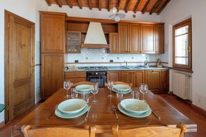 Una cucina con armadietti in legno, un tavolo da pranzo apparecchiato con piatti e bicchieri, e una finestra che offre luce naturale.