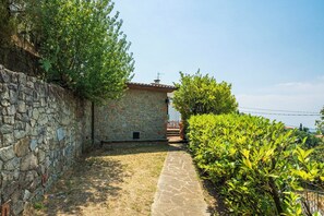 A stone pathway leading to a rustic building with a tiled roof, surrounded by lush greenery and a clear sky. - Vacation Home in Lamporecchio with 1 bedrooms sleeps 4 (Lamporecchio)