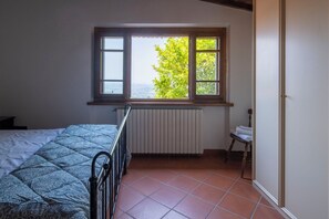 A bedroom with a bed, a window with a view, a radiator, and a small table. - Vacation Home in Lamporecchio with 1 bedrooms sleeps 4 (Lamporecchio)